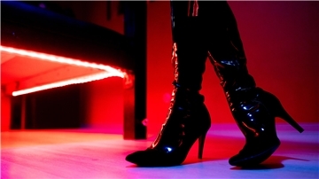  Eine Prostituierte steht vor der roten Beleuchtung unter einem Bett in einem Studio. 