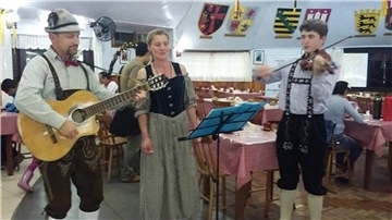 Zwei Männer spielen Instrumente und eine Frau singt dazu.  