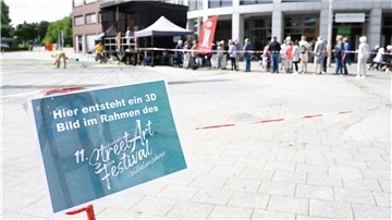 11. Internationales StreetArt-Festival: Vor dem riesigen 3D-Motiv am Valoisplatz in Wilhelmshaven hat sich eine lange Warteschlange gebildet.