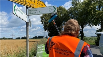 Ein Mann steht vor Straßenschildern.