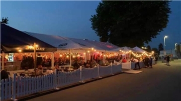 Mit Girlanden beleuchteter Biergarten am Abend