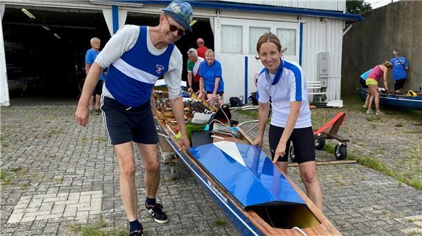 Ein Mann und eine Frau tragen ein Boot zu Wasser