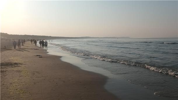 Eine Gruppe von Menschen läuft am Strand entlang. 