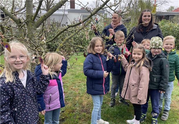 Eine Kindergartengruppe schmückt einen Baum zu Ostern.