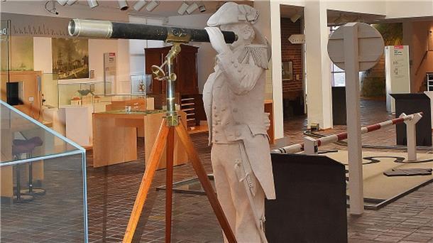 Eine weiße Skulptur eines historischen Admirals hält in den Ausstellungsräumen des Historischen Museums ein auf einem Stativ stehendes Fernrohr in der Hand.