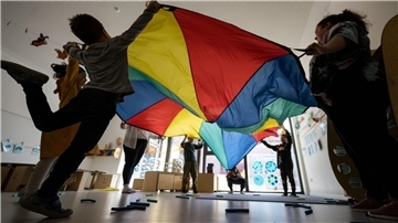 Kinder und Erwachsene spielen mit großem Tuch