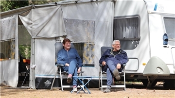 Camping für Einsteiger: Diese Tipps vom Experten helfen beim Urlaub auf Rädern Ein Ehepaar sitzt vor einem Campingwagen. Alles andere als Neuling sind Marta und Uwe Baars. Sie campen seit 40 Jahren und wissen, was beim Campingurlaub nicht fehlen darf.