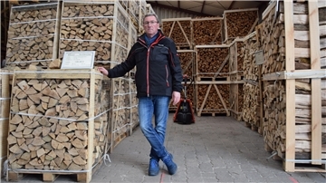 Ein Mann zwischen Holzstapeln auf Paletten
