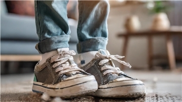 Ein Kind mit kaputten Schuhen.
