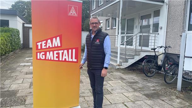 Mann neben Aufsteller der IG Metall
