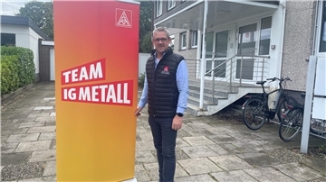 Mann neben Aufsteller der IG Metall