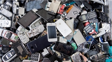 Alte Handys und Smartphones liegen in einem Container, ehe sie geschreddert werden.