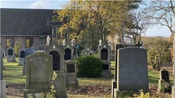 Alter Friedhof in Grafel mit traditionellen Engelfiguren aus Bisquitporzellan, die tages- oder jahreszeitlicher Dunkelheit mit strahlendem Weiß begegnen.