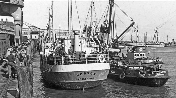 Vor 70 Jahren: Die Seenotretter finden die im Herbststurm vermisste „Nossan“ Schwarz-Weiß-Aufnahme: Drei Schiffe liegen hintereinander an einer Pier im Hafen von Cuxhaven.