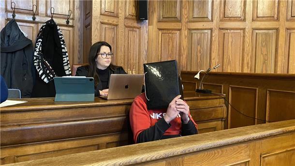 Ein Mann sitzt auf einer Bank und verdeckt sein Gesicht. 