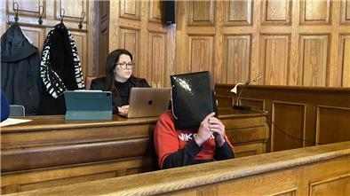Ein Mann sitzt auf einer Bank und verdeckt sein Gesicht. 