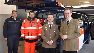 Mehrere Herren stehen nebeneinander. Dahinter befindet sich das neue Einsatzfahrzeug der Johanniter.