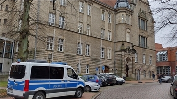 Ein Polizeibus und viele Autos parken vor dem Stader Landgericht.