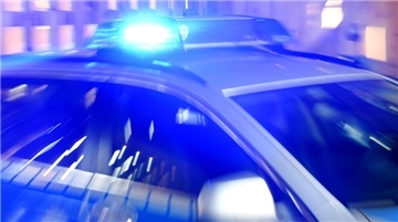 Ein Streifenwagen der Polizei steht mit eingeschaltetem Blaulicht auf der Strasse.