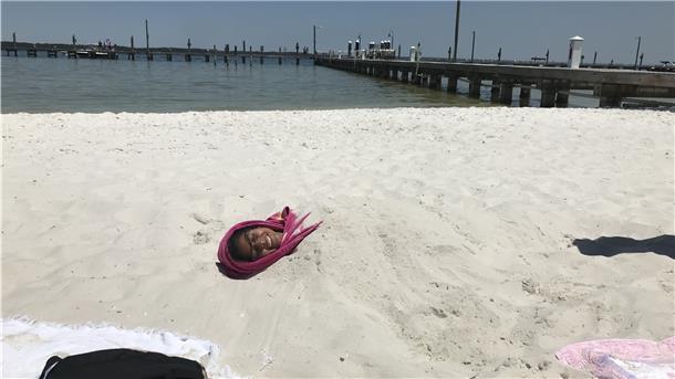 Covid, Orkane und ein bisschen Hoffnung Eine Frau liegt verbuddelt am Strand von Santa Rosa Sound Beach.