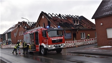 Ein Feuerwehrfahrzeug steht in dem Ort Beverstedt vor den Häusern.  Je zwei Wohn- und Geschäftsgebäude gerieten am Wochenende in Brand.