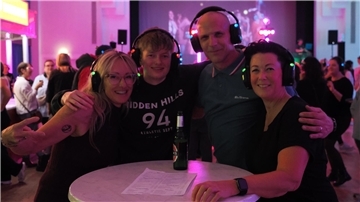 Menschen feiern in der Stadthalle Nordenham und haben Kopfhörer auf.