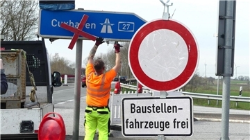 An der Anschlussstelle Uthlede entfernen Bauarbeiter die Verkehrszeichen, die auf die Sperrung der A27 hinweisen.