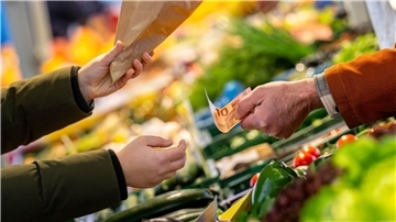 An einem Marktstand wird mit Bargeld eingekauft: Höhere Teuerungsraten schmälern die Kaufkraft von Verbrauchern.