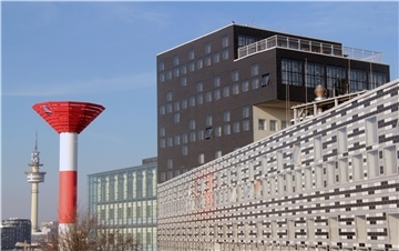 Ein Hochhaus, daneben ein Leuchtfeuer und ein Radarturm.