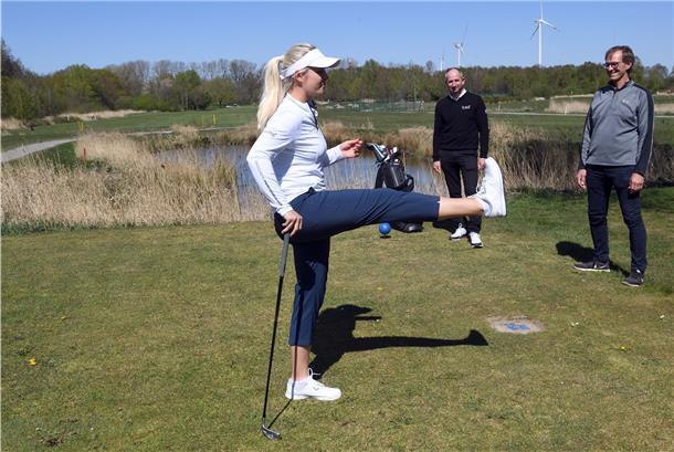 Anastasia Mickan macht Übungen. Mit im Bild: Golfpro Oliver Kremer (Mitte) und Clubmanager Thomas Koch (rechts).