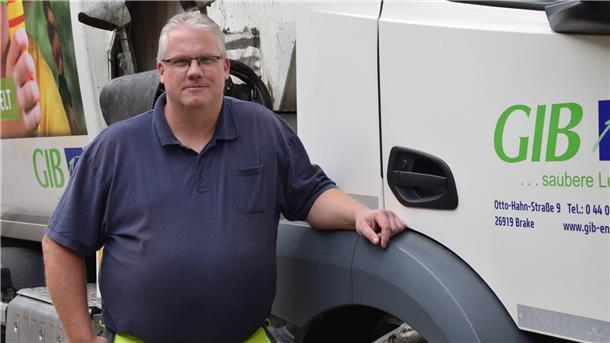 Es ist der Fahrer Andre Plate zu sehen, der neben seinem Fahrzeug steht. 