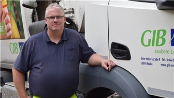Es ist der Fahrer Andre Plate zu sehen, der neben seinem Fahrzeug steht. 