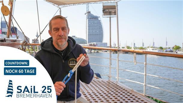 Ein Mann sitzt in Bremerhaven an Bord der „Schulschiff Deutschland“ und erklärt den Schotstek – einen Seemannsknoten.