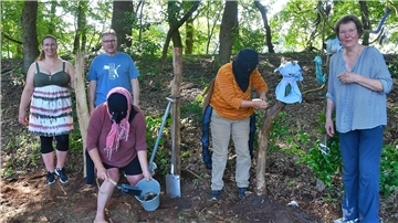 Andrea Priess (vorne) ist als Nashornkäfer verkleidet, Imke Tiedemann (Dritte von links) als Blattschneiderbiene. Gemeinsam mit (von links) Patricia und René Gerhardt sowie Barbara Mohrmann zeigen sie den Besuchern, wie man Totholz für den Insektenschutz nutzen kann.