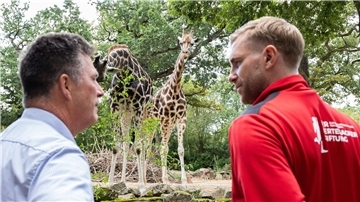 Andreas Casdorff (l), Geschäftsführer vom Erlebnis-Zoo Hannover, und Per Mertesacker, ehemaliger Fußballnationalspieler, stehen am Rand eines Geheges mit Rothschild-Giraffen.