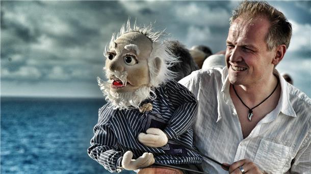 Ein Mann und eine Handpuppe in Form eines Kapitäns.