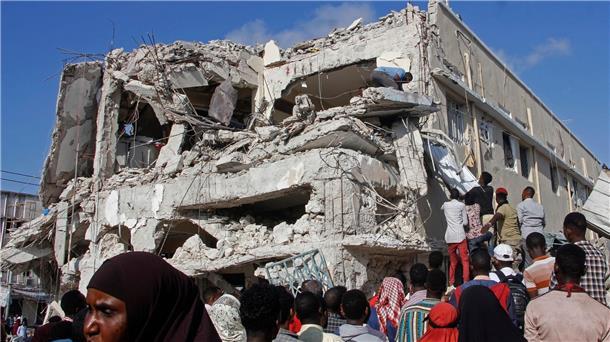 Angehörige  warten darauf, dass die Leichen von dem Ort entfernt werden, wo am Vortag zwei Autobomben an einer belebten Kreuzung in Mogadischu in Somalia eingeschlagen sind.