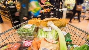 Ein Einkaufswagen in einem Supermarkt, gefüllt mit Gemüse.