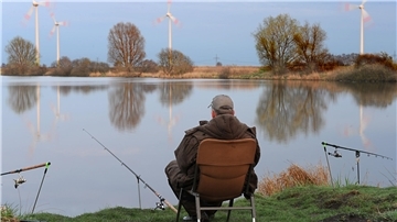 Ein Angler sitzt an einem Fluss.