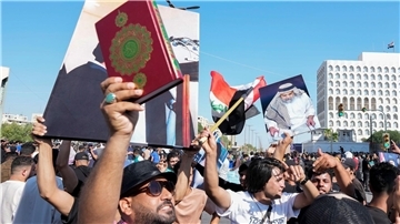 Anhänger des schiitischen Geistlichen Muqtada al-Sadr erheben den Koran, das heilige Buch der Muslime, während einer Demonstration vor der schwedischen Botschaft in Bagdad.