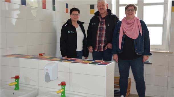 Drei Erwachsene stehen in einem Bad für Kinder. 