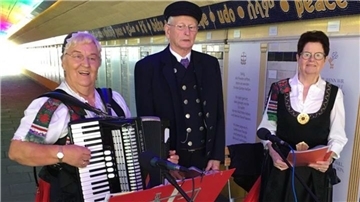 Zwei Frauen und ein Mann in der Mitte singen und musizieren.
