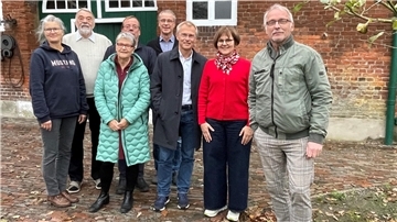 Gruppe von Menschen vor einem Bauernhof