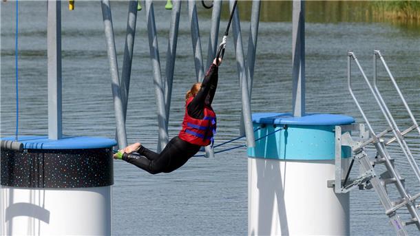 Eine Frau schwingt sich an einem Ring ins Wasser