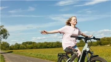 Annika fährt auf einem Feldweg freihändig Fahrrad.