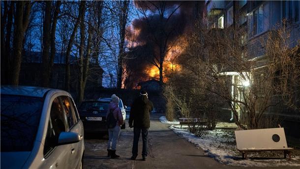 Anwohner beobachten ein brennendes Gebäude in Kiew, das bei einem Drohnenangriff getroffen wurde.