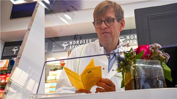 Ein Apotheker prüft einen Impfausweis.