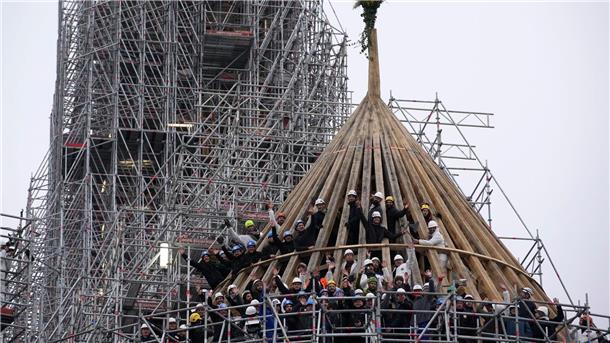 Arbeiter feiern den Abschluss des Wiederaufbaus des Dachstuhls der Kathedrale Notre Dame mit einem traditionellen Blumenstrauß.