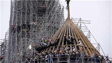 Arbeiter feiern den Abschluss des Wiederaufbaus des Dachstuhls der Kathedrale Notre Dame mit einem traditionellen Blumenstrauß.
