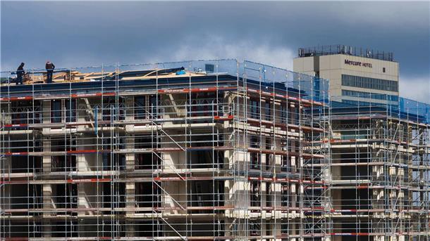 Arbeiter stehen auf dem Dach eines Rohbaus. Der Bundesverband deutscher Wohnungs- und Immobilienunternehmen benötigt mehr Geld für den klimagerechten Neubau.